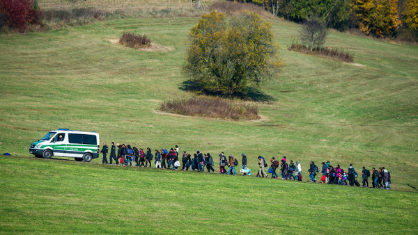 Auf dem Höhepunkt der Flüchtlingskrise im Herbst 2015: Migranten gehen hinter einem Fahrzeug der Bundespolizei in Bayern.