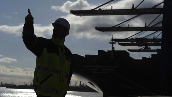Handelsknoten: Ein Arbeiter beaufsichtigt ein Containerschiff im Hamburger Hafen