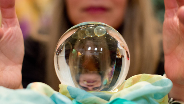 Eine Wahrsagerin blickt auf der Stuttgarter Esoterik-Messe in eine Kristallkugel.