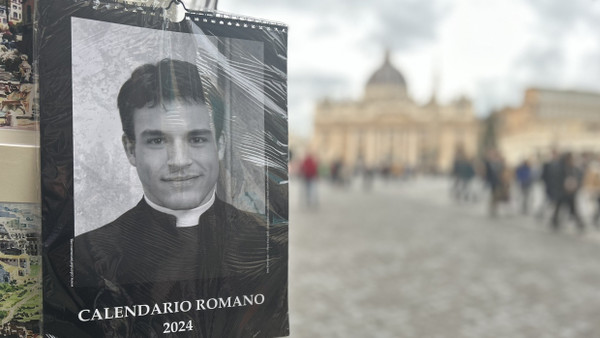 Der „Calendario Romano“ an einem Souvenirstand, im Hintergrund der Petersdom in Rom.
