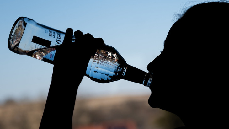 Ein Mädchen trinkt aus einer Flasche Wodka.