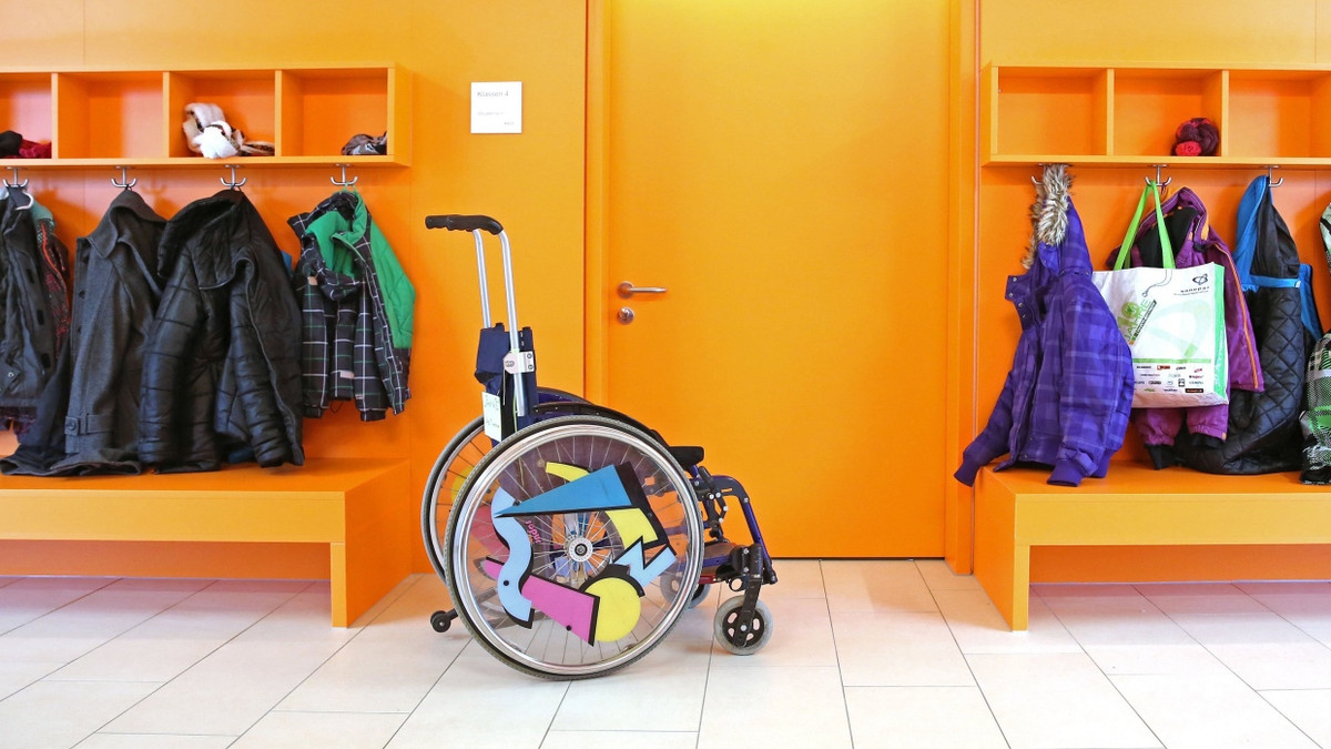 Ein Rollstuhl steht vor einem Klassenzimmer.