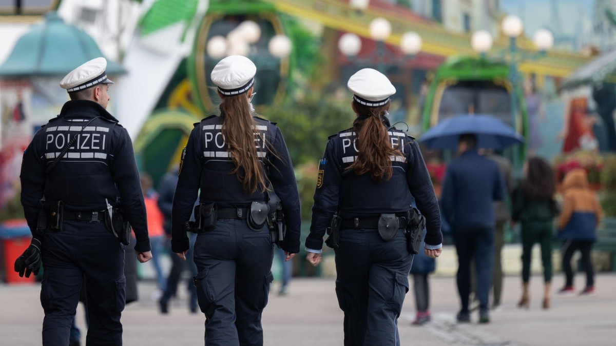 Polizisten gehen zu Beginn des Frühlingsfests in Stuttgart über das Festgelände.
