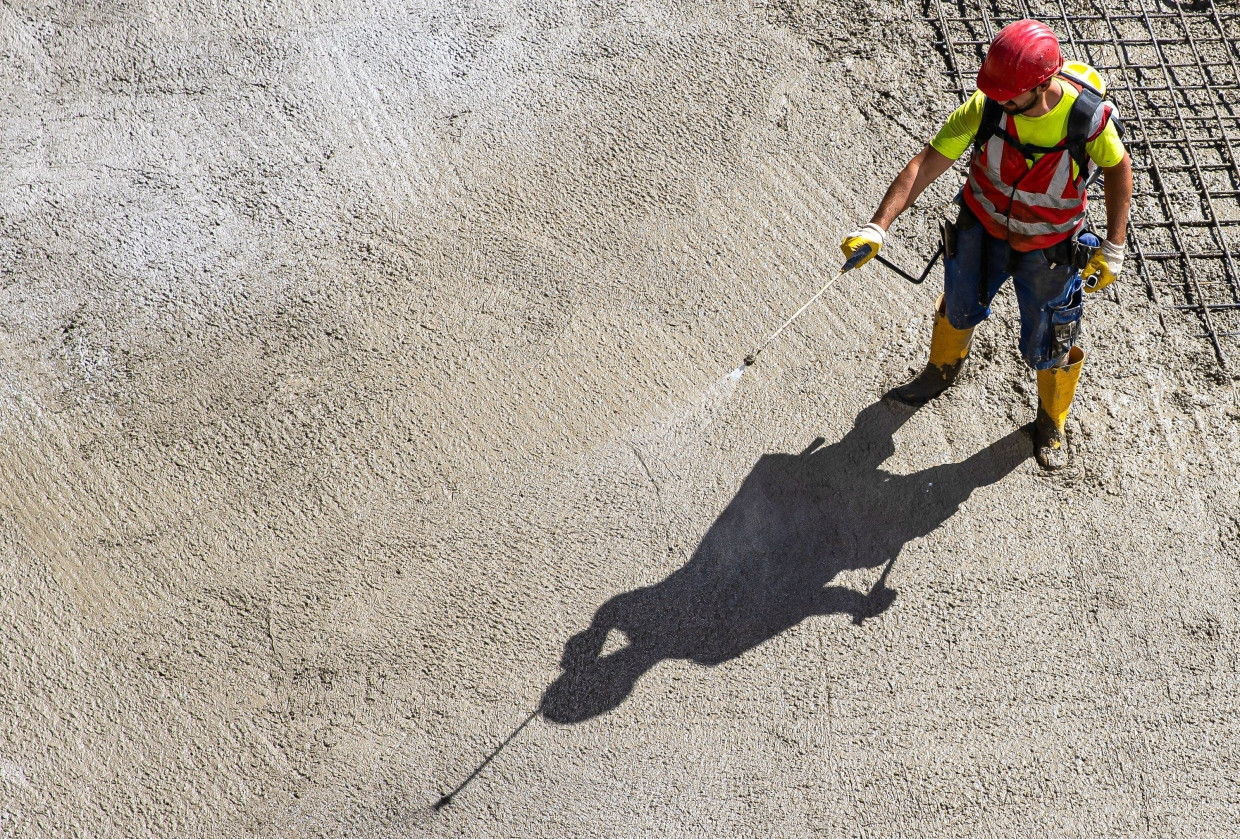 Ein Bauarbeiter auf einer Hochhausbaustelle mit frischem Beton. Bei dessen Herstellung werden bisher tonnenweise Treibhausgase frei.