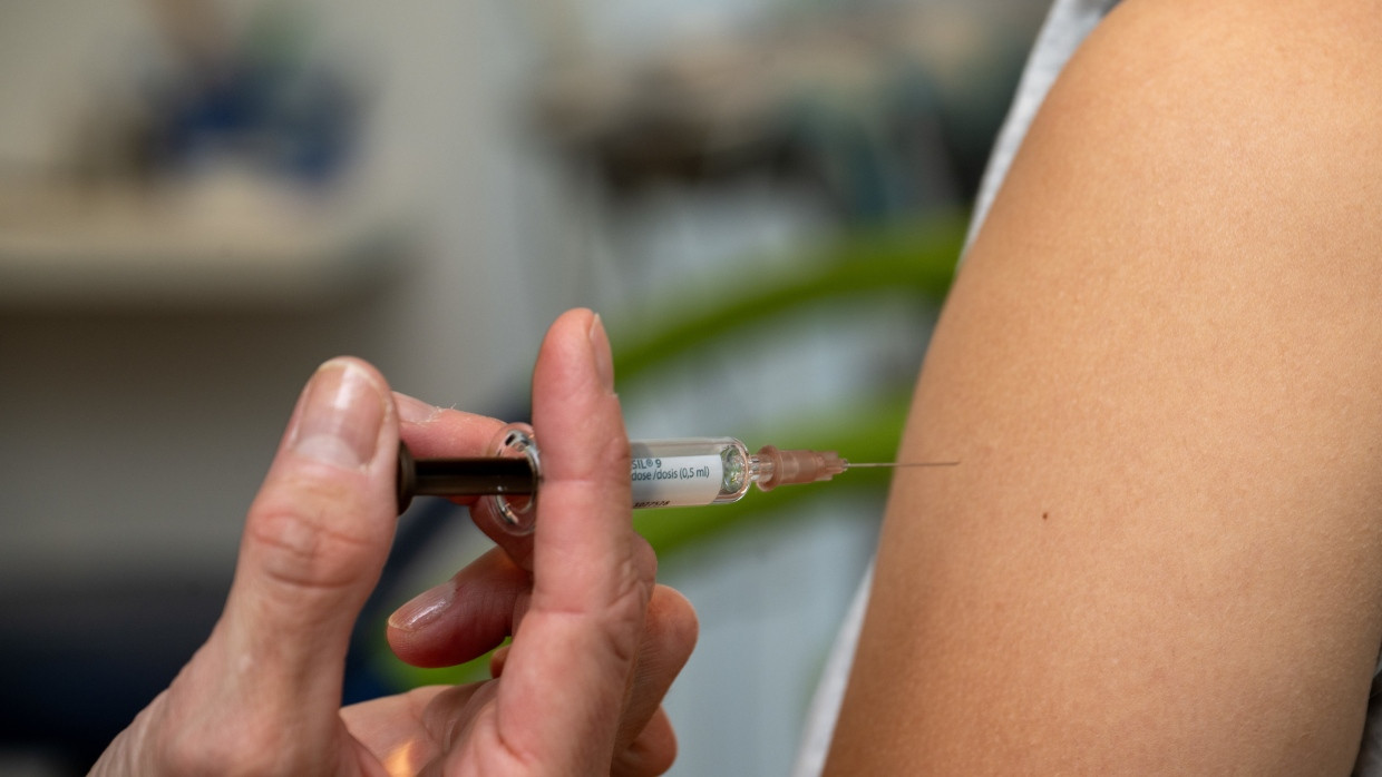 Eine Gynäkologin setzt bei der HPV-Impfung in einer Frauenarztpraxis eine Injektion in den Oberarm einer Jugendlichen.