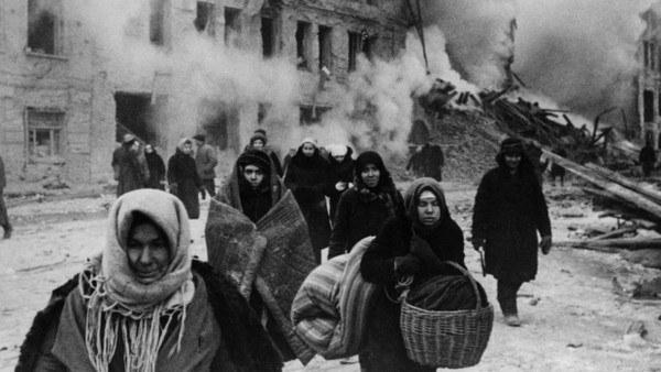 Epochales Verbrechen: Nach einem Bombenangriff der Deutschen Armee auf das von Versorgungswegen abgeschnittene Leningrad fliehen Menschen aus ihren zerstörten Häusern.