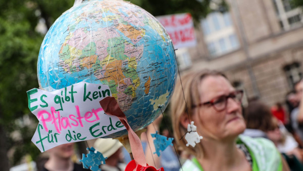 Eine Demonstrantin bei einem Klimaprotest der Gruppe Fridays for Future in Berlin trägt einen beschrifteten Globus.