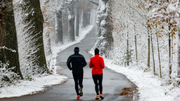 Zwei Personen laufen warm angezogen im Winter.