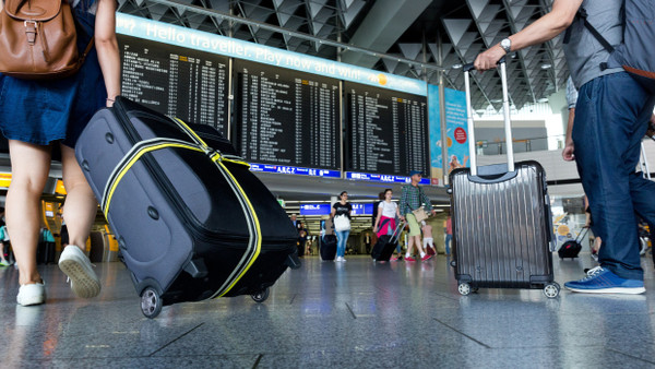 Touristen mit Rollkoffer im Frankfurter Flughafen