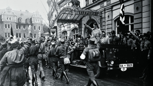 Stadt mit Symbolkraft: Während eines Kongresses der thüringischen NSDAP in Frühjahr 1930 posieren vor dem Weimarer Hotel Elephant in einem offenen Mercedes stehend Adolf Hitler, dahinter Hitlers Privatsekretär und persönlicher SS-Adjutant Rudolf Heß (in hellem Mantel) sowie NSDAP-Gauleiter Fritz Sauckel.