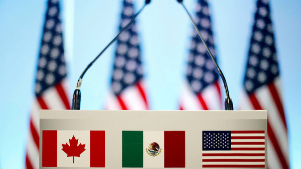 Die Flaggen von Kanada, Mexiko und den Vereinigten Staaten auf einem Rednerpult.