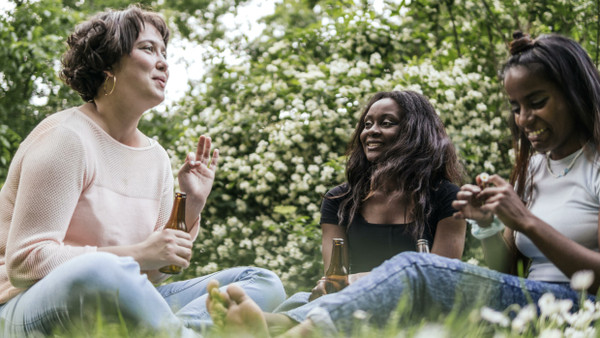 Drei Frauen sitzen gemeinsam im Park – ein Freundinnenerlebnis, dass mit zunehmendem Alter häufig seltener wird. (Symbolbild)