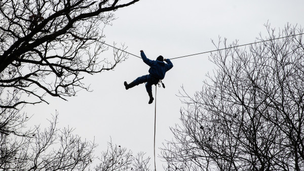 Im Fechenheimer Wald in Frankfurt hängt im Januar 2022 während der polizeilichen Räumung ein Aktivist an einem Seil zwischen Bäumen.