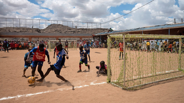 Match vor den Müllbergen: Durch die Ayiera-Initiative sollen Jugendliche durch Bildung und Sport einen Weg aus dem Slum, fort von der Deponie finden, die hinter dem Bolzplatz in den Himmel ragt.