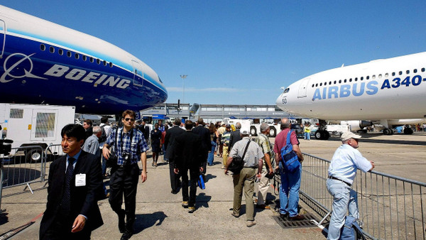 Besucher der Luftfahrtmesse im französischen Le Bourget gehen zwischen einer Boeing 777 (links) und einem Airbus A340 hindurch.