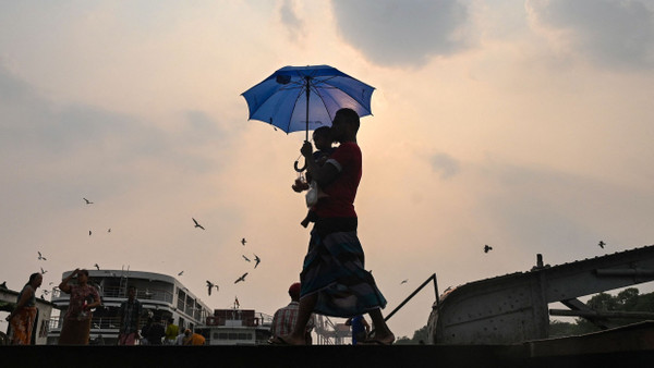 Durch das globale Klimaphänomen El Niño könnten sich Extremwetter weiter häufen: Während einer Hitzewelle im April 2023 in Myanmar schützt ein Mann seinen Sohn mit einem Schirm vor der Sonne.