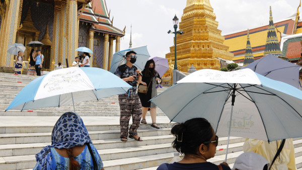 Nur mit Sonnenschirm ins Freie: Touristen in Bangkok schützen sich vor der Hitze.