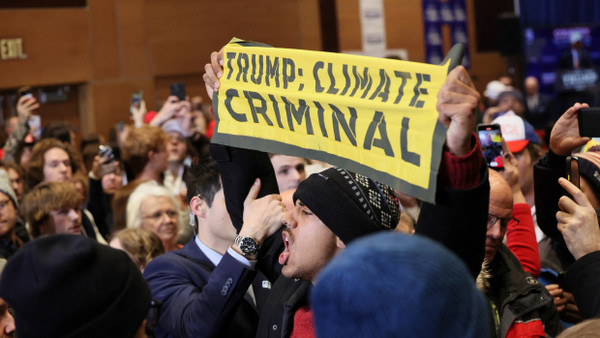 Ein Klimaaktivist hält einen Banner mit den Worten „Trump, Klimaverbrecher“ bei einer Wahlkampfveranstaltung des ehemaligen Präsidenten Donald Trump in Indianola im US-Bundesstaat Iowa.