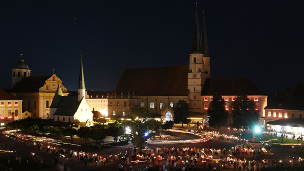 Gläubige umrunden bei einer Lichterprozession am Vorabend von Mariä Himmelfahrt mit Kerzen auf den Kapellplatz die Gnadenkapelle im bayerischen Altötting.