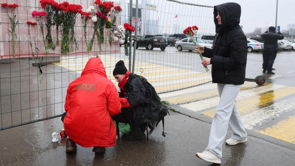 Passanten legen Blumen vor der „Crocus City Hall“ ab.