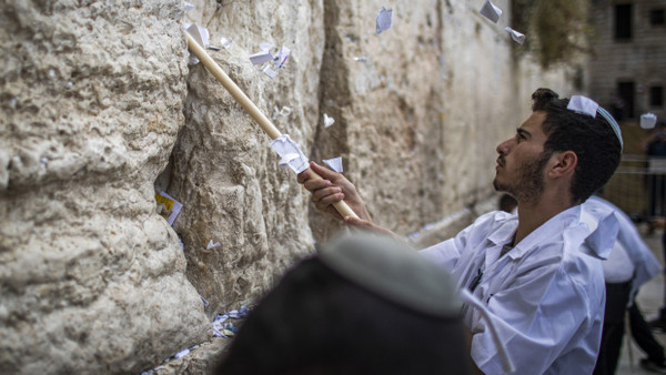 Ein Mann entfernt Gebetszettel aus der Klagemauer in Jerusalem.
