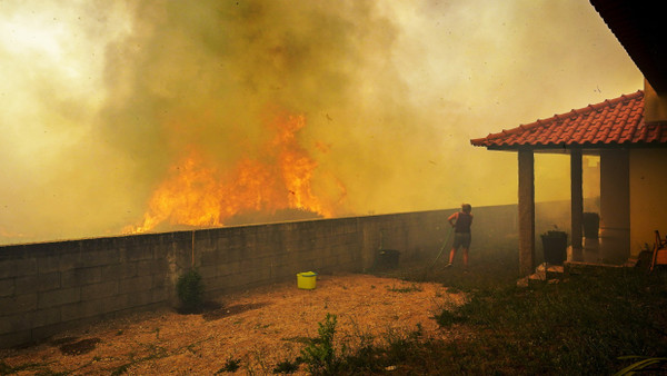 Eine Frau beobachtet von ihrem Grundstück aus ein Feuer im Norden von Portugal.