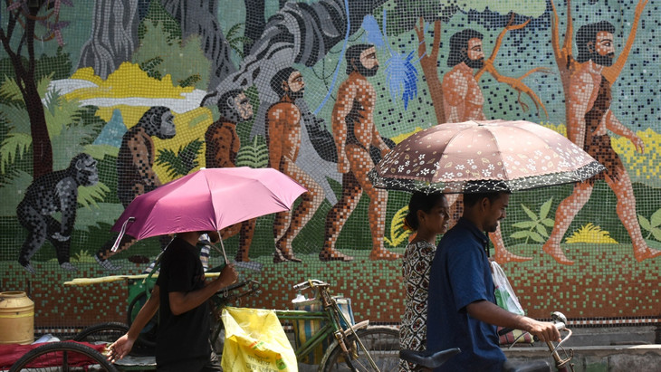 Menschen in Kolkata nutzen Schirme, um sich vor der Sonnenstrahlung zu schützen (Indien, 28. April 2024).