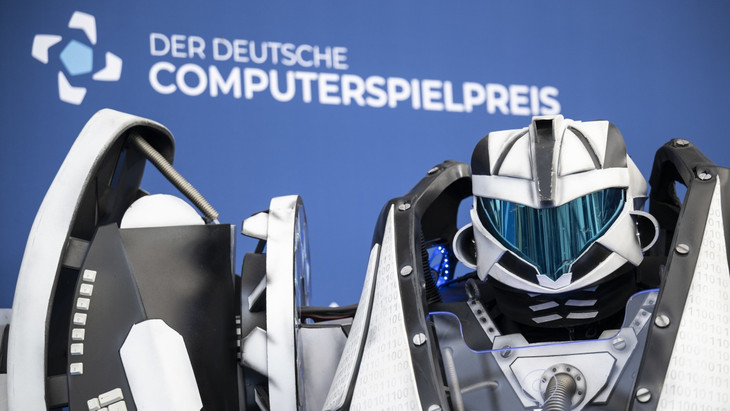 Computerzeit: Der Gamescom Bot steht vor der Fotowand des Deutschen Computerspielpreises