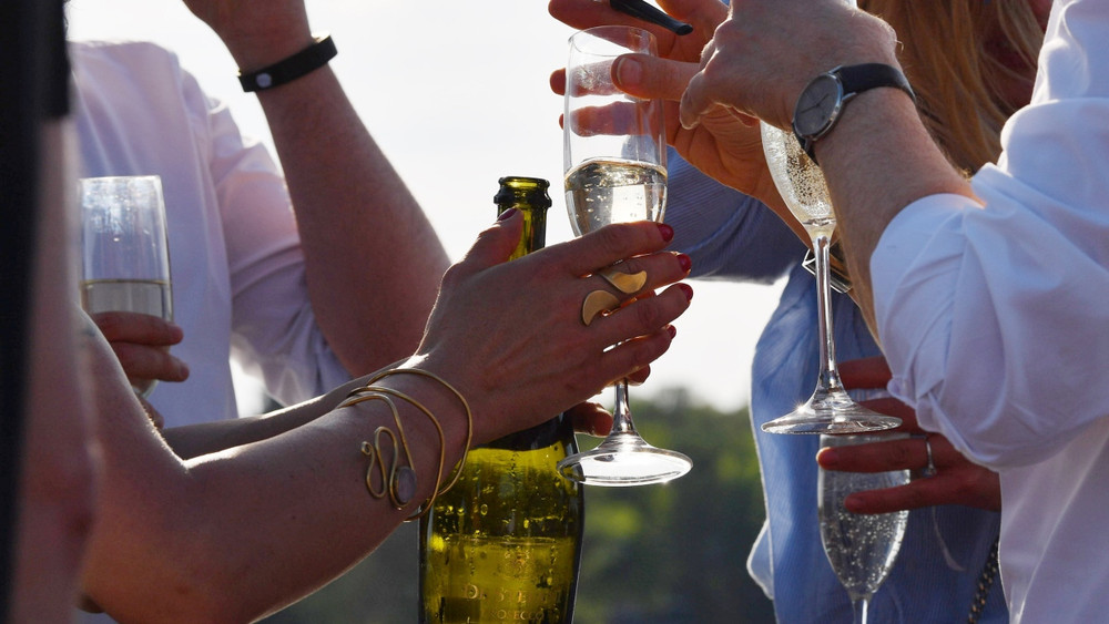 Partygäste halten Gläser mit Prosecco in den Händen.