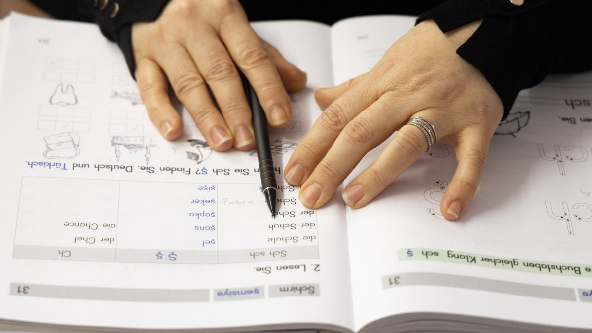 Eine Teilnehmerin arbeiten in einem Lehrbuch während ihres Sprachkurses.