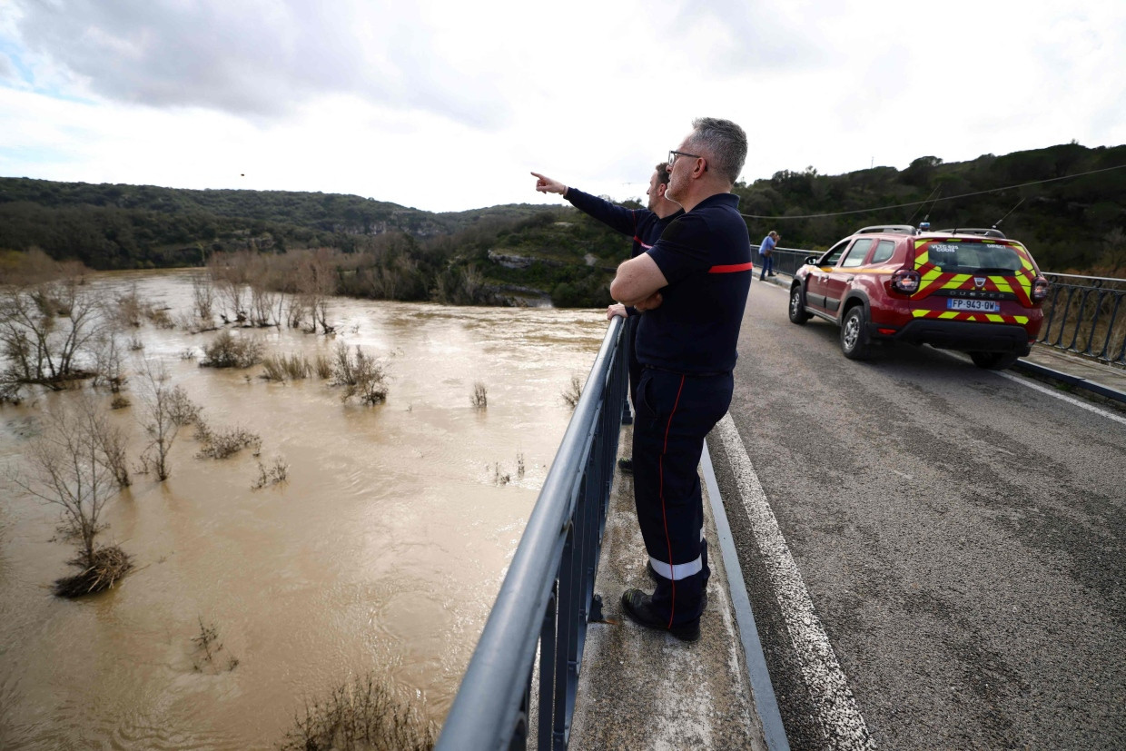 Feuerwehrmänner beobachten auf einer Brücke den überschwemmten Fluss Gardon.