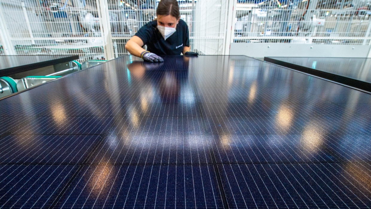 Eine Mitarbeiterin begutachtet in der Endkontrolle für Solarmodule im Werk der Meyer Burger Technology AG in Freiberg ein Solarmodul.
