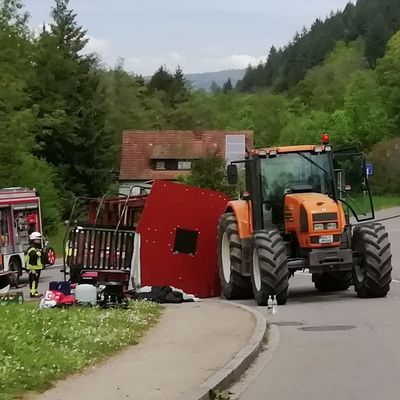 Rettungskräfte stehen nach einem Unfall neben einem einem umgestürzten Maiwagen. 