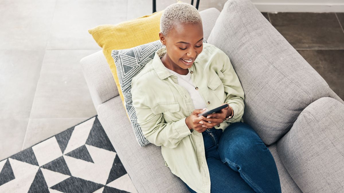 Woman, relax and typing with phone on sofa